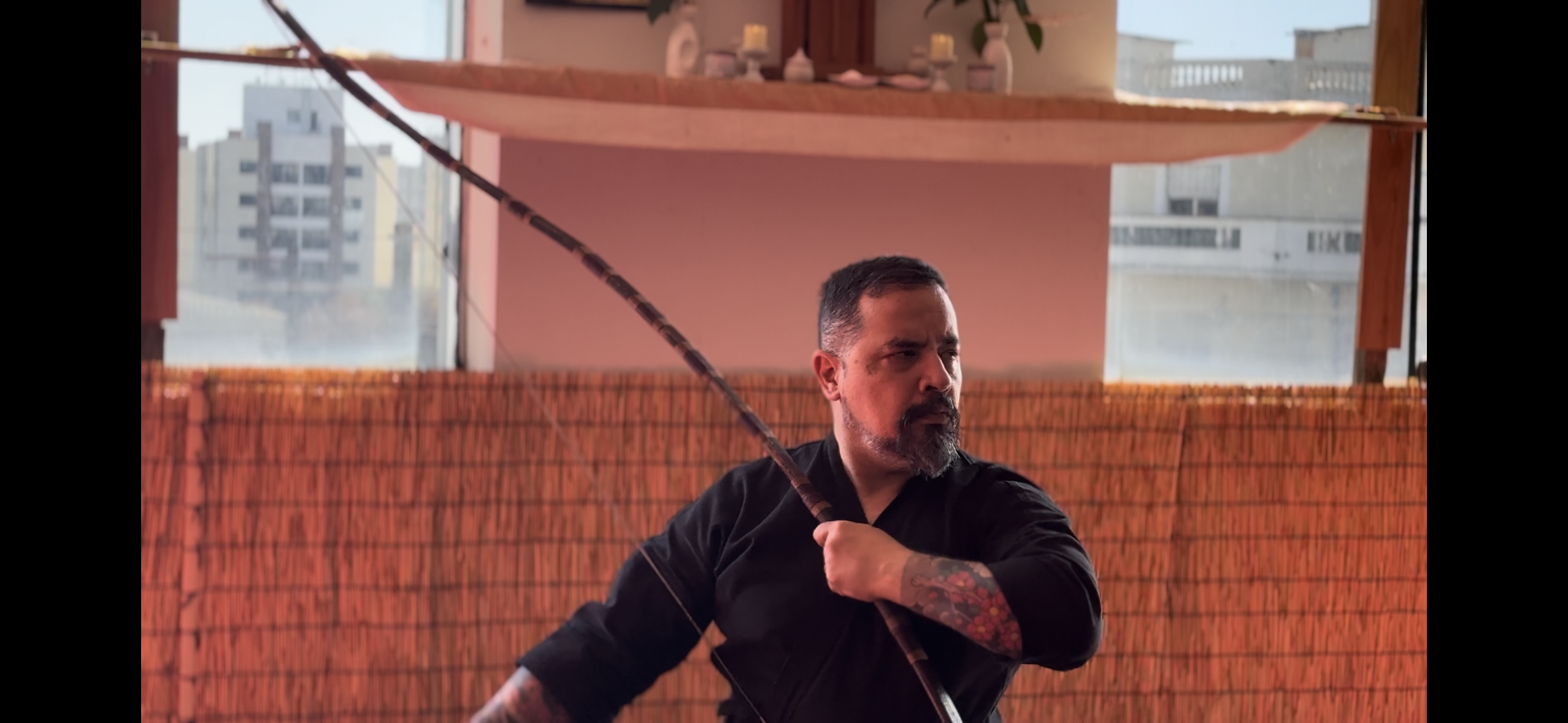 Jason Sensei segura o arco inclinado durante a prática