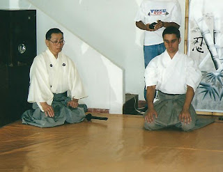 Akira Tsukimoto e Adriano Pereira sentados em um dojo